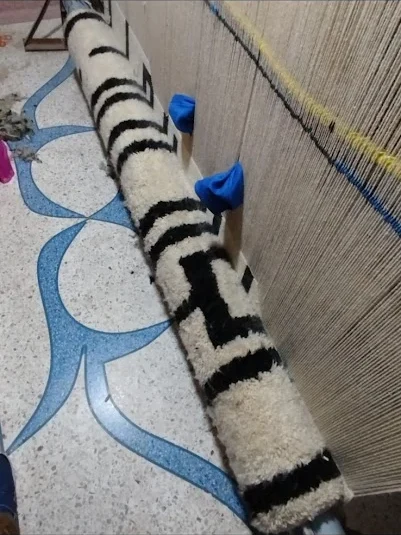 Finished rug rolled on the loom in black and white