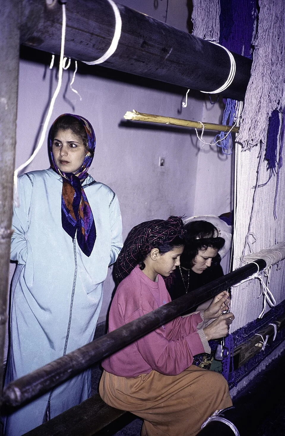 Amazigh artisans hand-knotting a Moroccan rug on a wooden loom