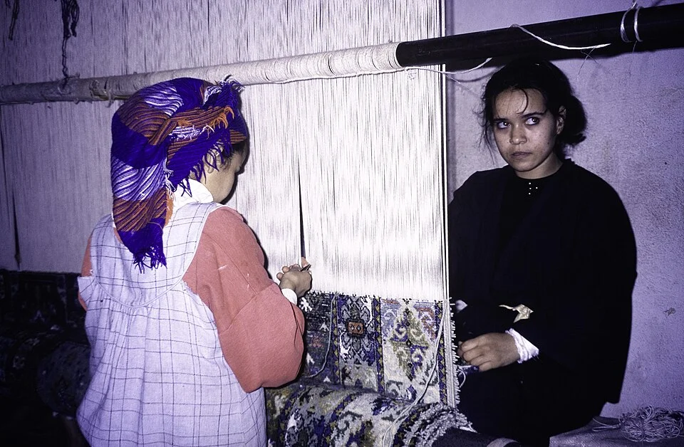 Two Amazigh weavers working side by side at the loom