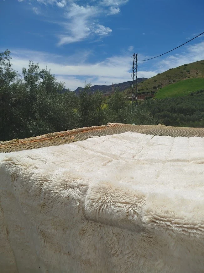 A finished Azral rug drying outdoors with the mountains behind