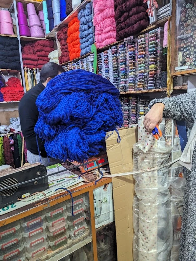 Testing commercial blue yarn at a wool shop in the souk